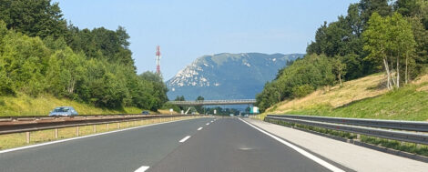 Eine Autobahn aus der Beifahrersicht. Links und rechts sind Böschungen mit Bäumen, geradeaus sieht mn ein Hochplateu