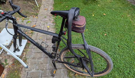 Ein Fahrradschlauch hängt auf dem Sattel eines Fahrrad, bei dem das Vorderrad ausgebaut ist.