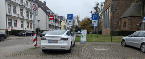 Ein Tesla steht an einer öffentlichen Ladesäule und parkt, ohne dass das Ladekabel angeschlossen ist.