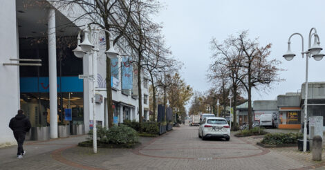 Ein Auto fährt durch eine Fußgängerzone.