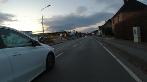 Ein Kfz wird zu dicht an einem Radfahrer vorbei gesteuert. Das Bild ist von einer am Lenker montierten Dashcam aufgenommen.