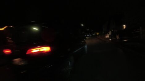 Ein eng überholendes Fahrzueg schert im Dunklen dicht vor einem Fahrradfahrer wieder ein. Das Bild wurde von einer Dashcam aufgenommen.