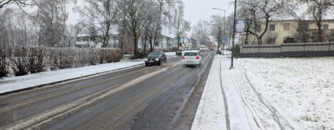 Auf einem nicht geräumten, verschneiten Geh- und Radweg sieht man Reifenspuren. Die Fahrbahnen der Straße sind frei, allerdings mit Schneematsch zwischen den Fahrspuren.